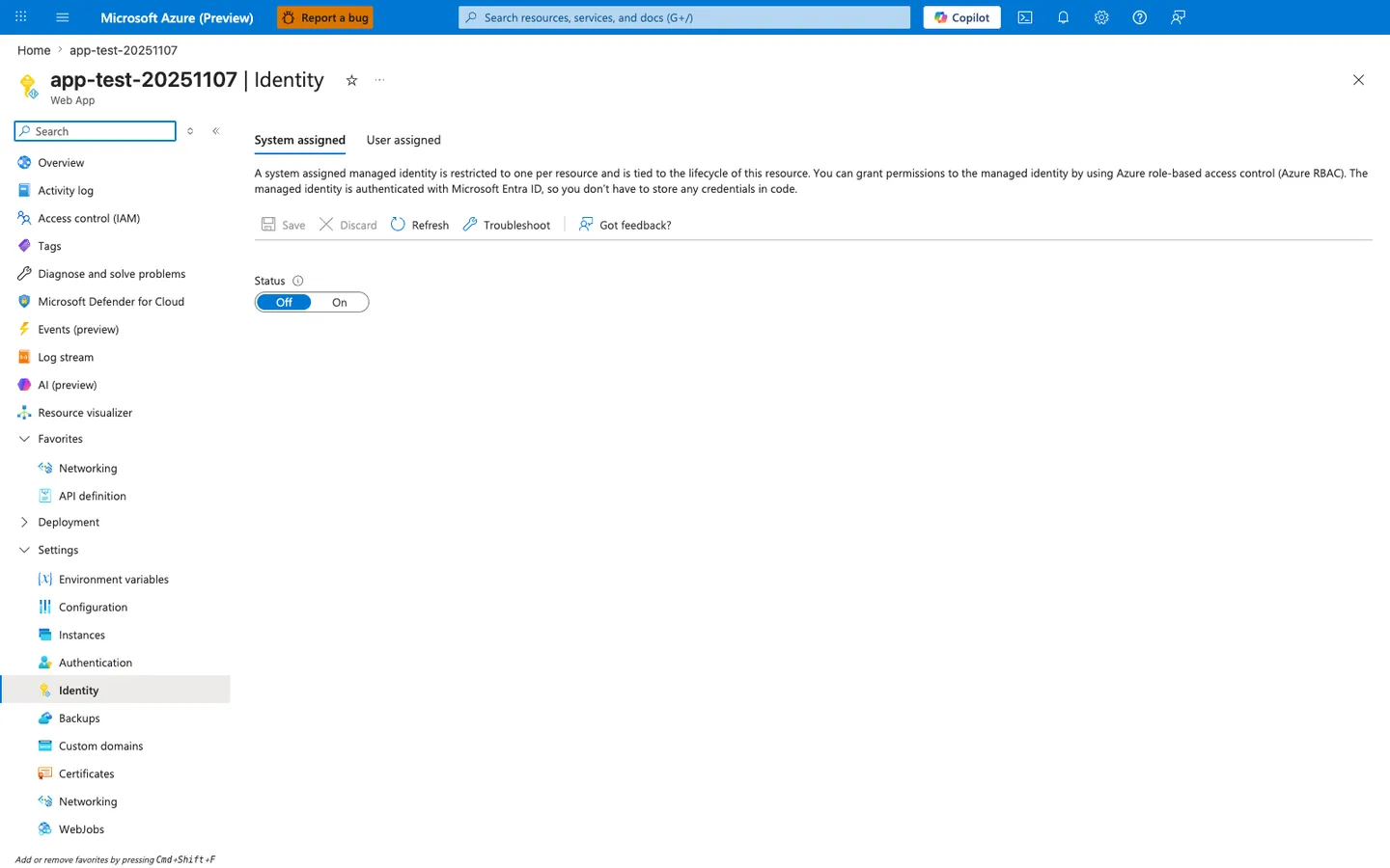 Identity blade for the `app-test-20251107` Web App showing tabs "System assigned" (selected) and "User assigned". The System assigned panel begins with the description "A system assigned managed identity is restricted to one per resource and is tied to the lifecycle of this resource. You can grant permissions to the managed identity by using Azure role-based access control (Azure RBAC). The managed identity is authenticated with Microsoft Entra ID, so you don't have to store any credentials in code." A command bar with Save, Discard, Refresh, Troubleshoot, and "Got feedback?" sits above a single Status toggle set to "Off" (Off/On) — no Object (principal) ID or Permissions section is shown because the identity is not yet enabled. The left navigation shows Identity selected under the Settings group.
