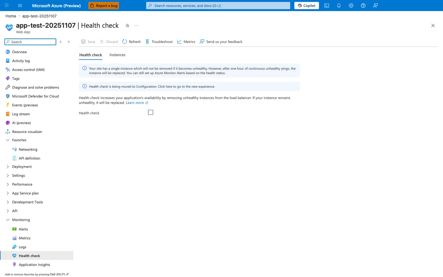 Azure portal Health check blade for app-test-20251107 with tabs Health check (active), Instances; toolbar buttons Save, Discard, Refresh, Troubleshoot, Metrics, Send us your feedback; info banner reading "Your site has a single instance which will not be removed if it becomes unhealthy. However, after one hour of continuous unhealthy pings, the instance will be replaced. You can still set up Azure Monitor Alerts based on the health status."; second info banner reading "Health check is being moved to Configuration. Click here to go to the new experience."; description text "Health check increases your application's availability by removing unhealthy instances from the load balancer. If your instance remains unhealthy, it will be replaced." followed by a Learn more link; a single Health check toggle row with the checkbox in the unchecked state; left service navigation showing Overview, Activity log, Access control (IAM), Tags, Diagnose and solve problems, Microsoft Defender for Cloud, Events (preview), Log stream, AI (preview), Resource visualizer, expanded Favorites with Networking and API definition pinned, and an expanded Monitoring group with Alerts, Metrics, Logs, Health check (selected), Application Insights.